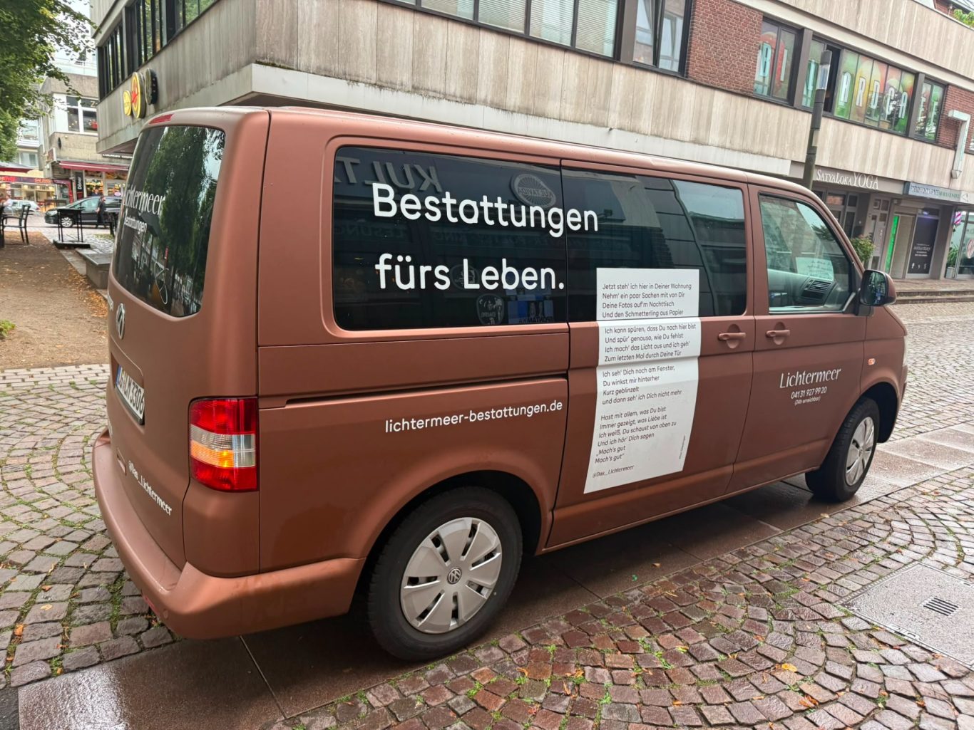 Bestattungswagen von Bestattung Lichtermeer vor dem Kultavida Kupferfarbener Bestattungswagen des Bestattungsinstituts Lichtermeer mit der Aufschrift „Bestattungen fürs Leben.“ vor dem Kultavida