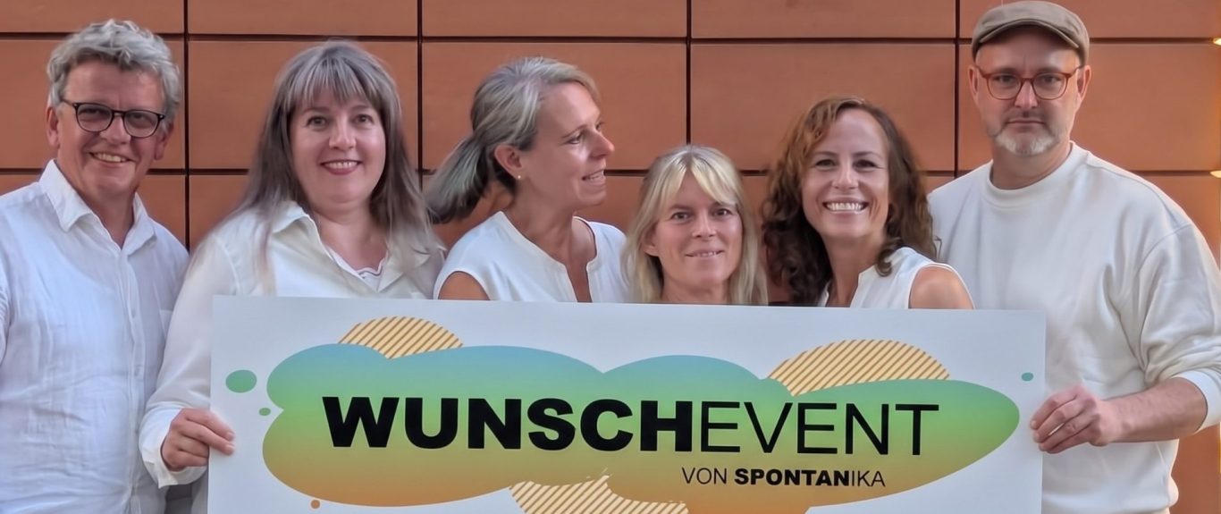 Das Ensemble von Spontanika Improtheater lacht gut gelaunt vor einer Backsteinwand bei einem kreativen Event im Kreis Stormarn.