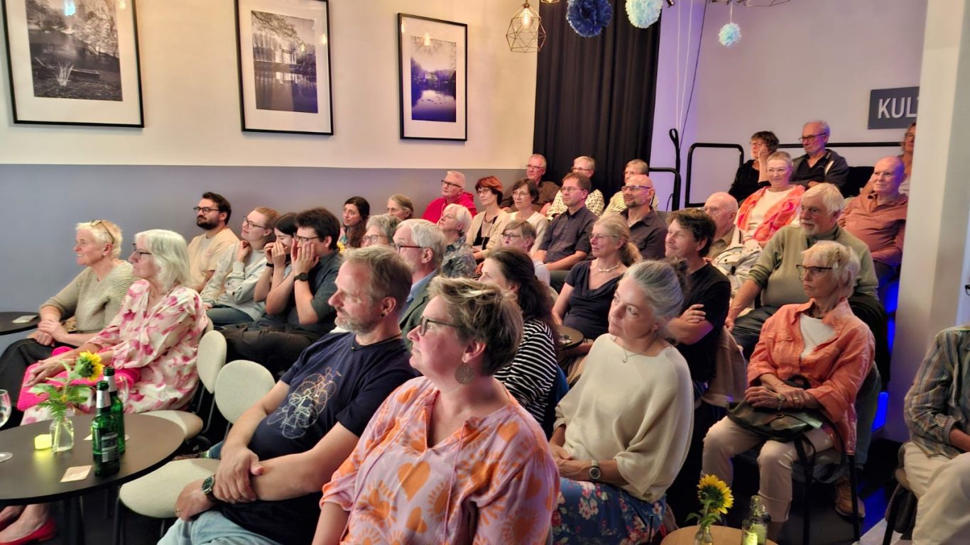 Publikum bei „Das letzte Lachen“ Gut gefüllter Veranstaltungsraum mit aufmerksamem Publikum während einer Improtheater-Aufführung der Show „Das letzte Lachen“.