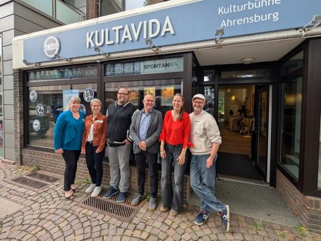 Pressefoto: Das letzte Lachen – KULTAVIDA Ahrensburg Das Projektteam der Kooperation „Das letzte Lachen“ steht lächelnd vor der Kulturbühne KULTAVIDA in Ahrensburg.
