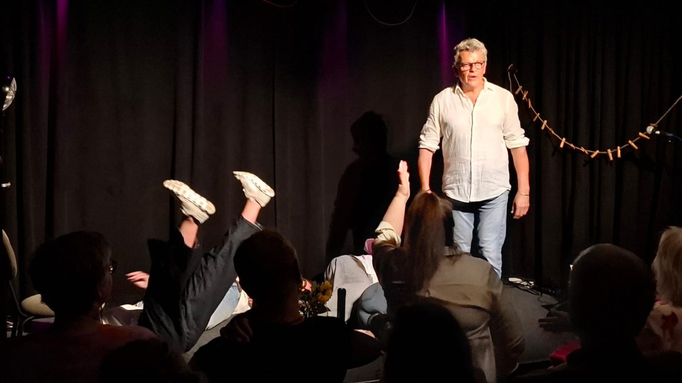 Impro-Game „Stirb!“ | Spontanika in Stormarn Spontanika-Darstellerinnen stehen auf der Bühne, während eine Person am Boden liegt – eine Szene aus dem Impro-Game „Stirb!“.