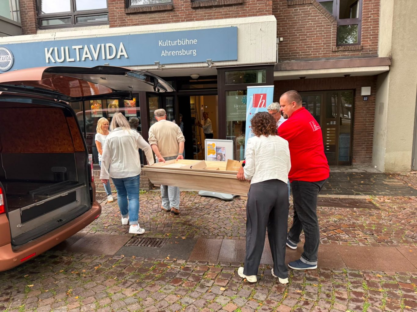 Sarglieferung vom Beerdigungsinstitut Lichtermeer ins Kultavida Personen tragen einen Sarg vom Beerdigungsinstitut Lichtermeer durch den Eingang in die Kulturbühne Kultavida für „Das letzte Lachen“