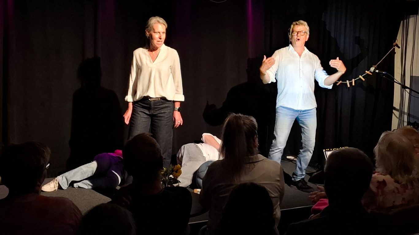 Impro-Game „Stirb!“ | Spontanika in Stormarn Spontanika-Darstellerinnen stehen auf der Bühne, während eine Person am Boden liegt – eine Szene aus dem Impro-Game „Stirb!“.