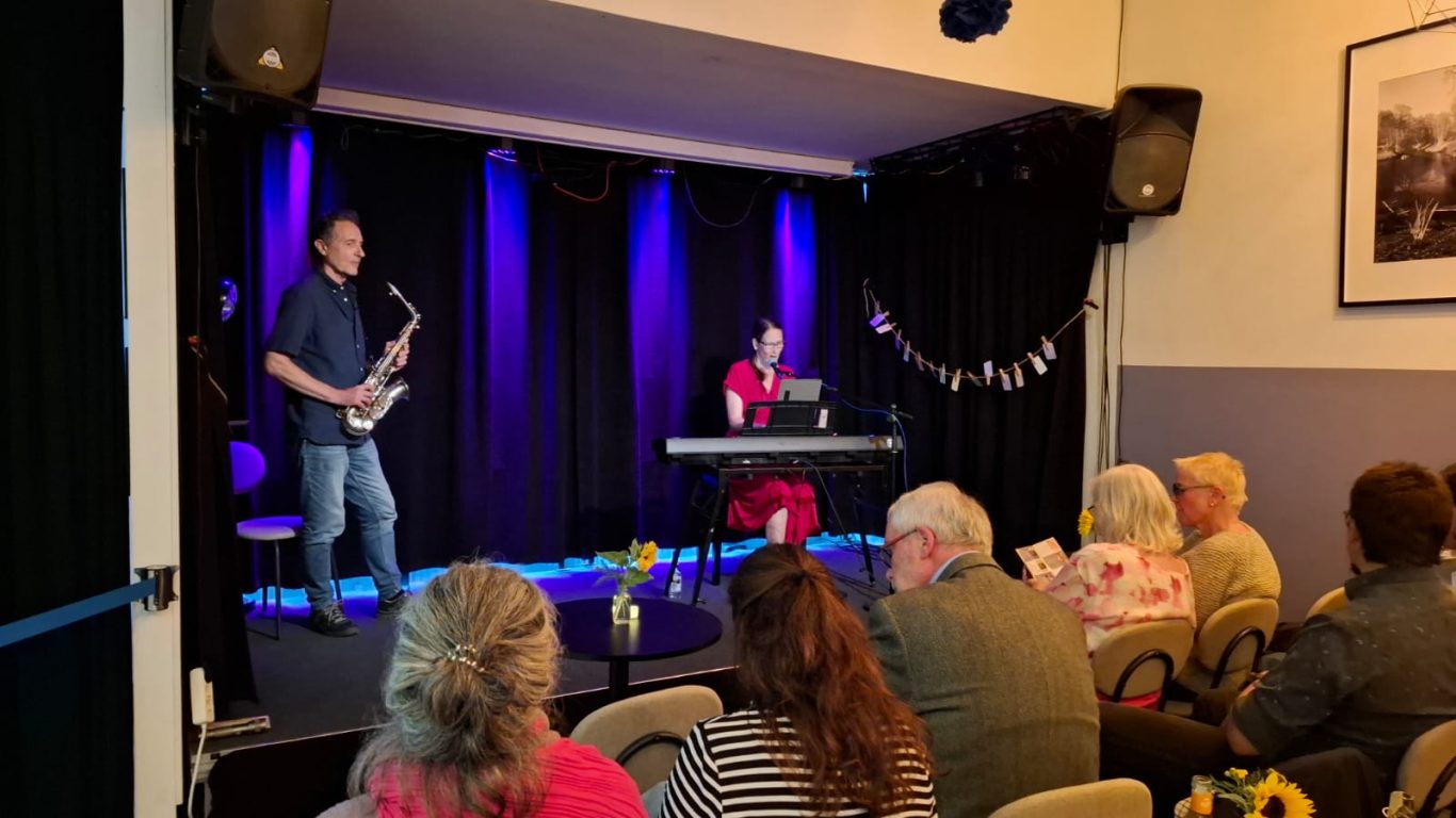 Musikalische Begleitung bei „Das letzte Lachen“ Live-Musik von Stephanie Arndt auf der violett beleuchteten Bühne im Kultavida vor Publikum.