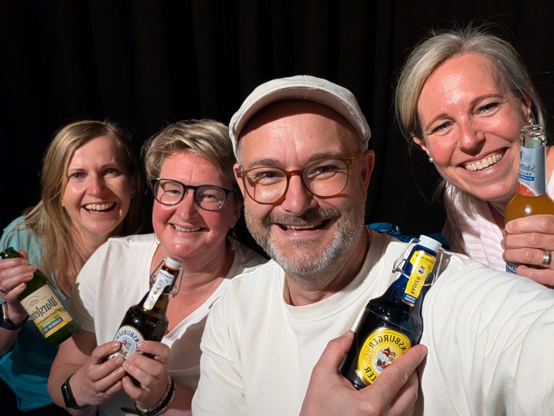 Spontanika Improwerkstatt – Vatti macht Theater Gruppenbild Gut gelaunte Teilnehmerinnen und Trainer beim Anstoßen nach dem Improtheater-Workshop „Vatti macht Theater“ in der Spontanika Improwerkstatt