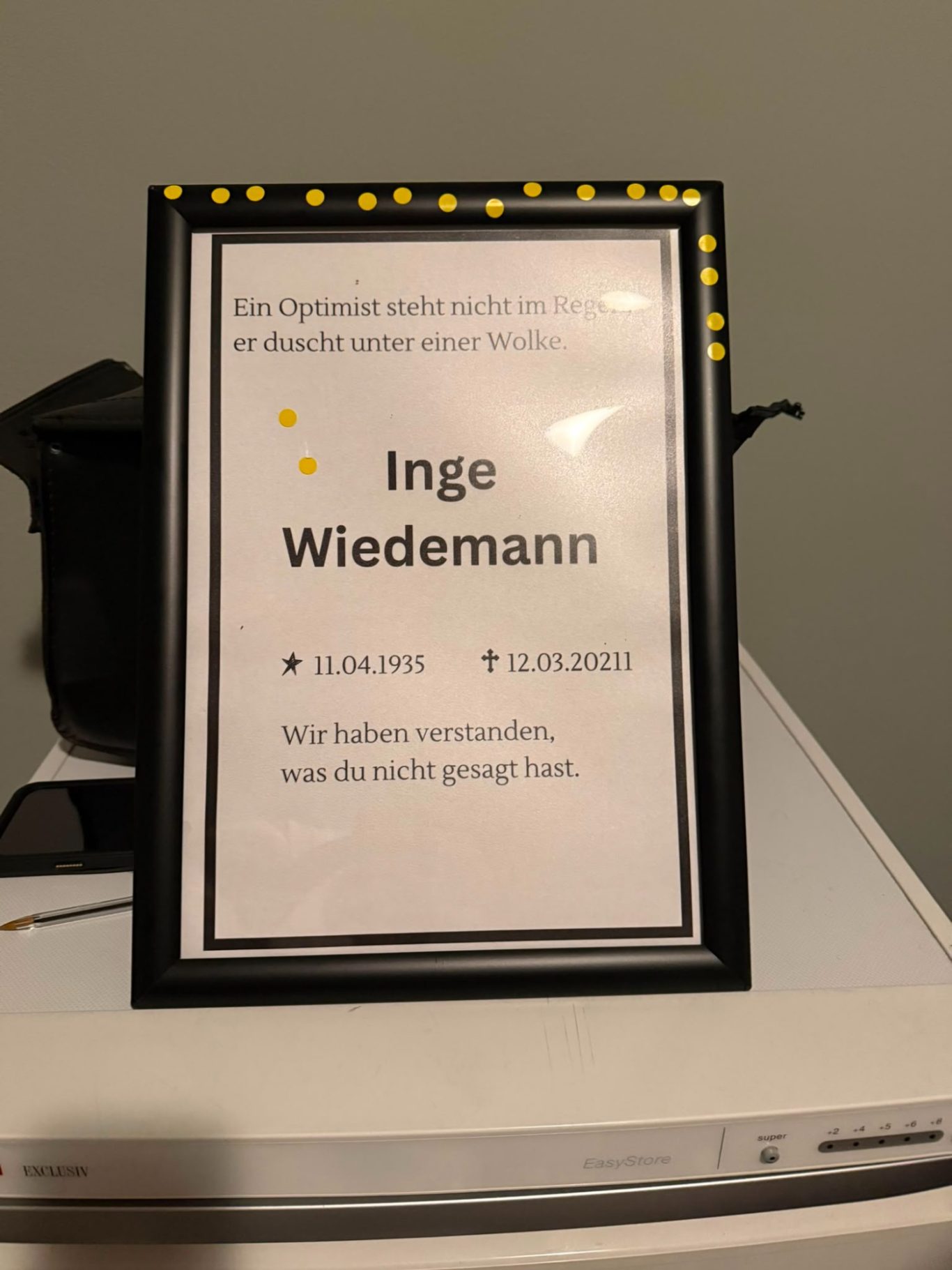 Requisite für die Langform bei „Das letzte Lachen“ im Kultavida Ein gerahmtes Schild mit der Aufschrift „Inge Wiedemann“ und Lebensdaten als Requisite für die Langform-Improvisation bei „Das letzte Lachen