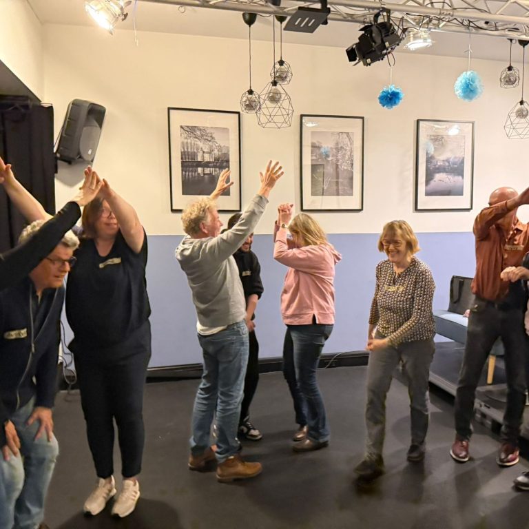 Ankommen und Lockermachen Eine Gruppe von Menschen streckt bei einer gemeinsamen Improtheater-Übung im Raum die Arme nach oben